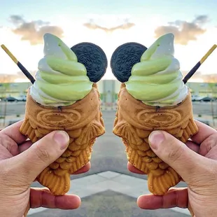 a pair of hands holding two ice cream cones