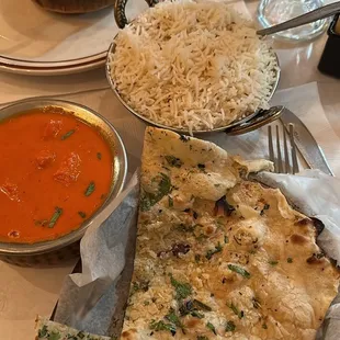 a plate of naan bread, a bowl of soup, and a glass of orange juice