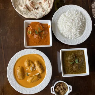 Top left Naan, rice, chicken Masalaa, Lamb Saag, Kofta Curry and assorted pickles on bottom right.