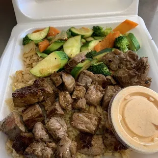 a takeout box with a variety of vegetables and meat