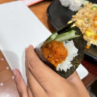 a person holding a piece of sushi