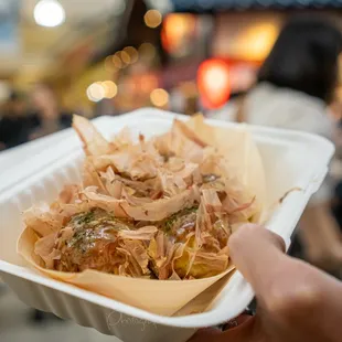 a person holding a take out container of food