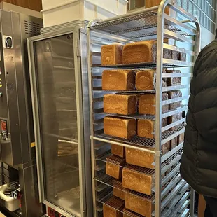 a person standing in front of a rack of bread