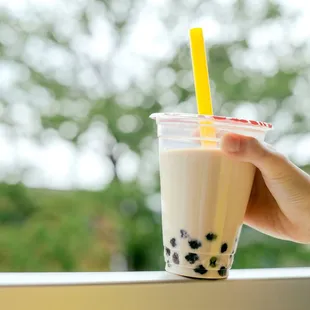 a hand holding a plastic cup of boba