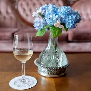 a glass of wine and a vase of flowers