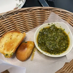 Complimentary bread (partially eaten) and fresh herb sauce/oil