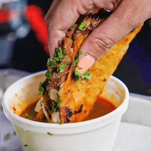  a hand dipping a tortilla