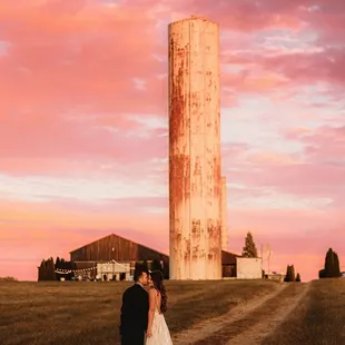 a bride and groom standing in front of a silo