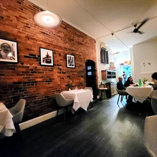 a restaurant with tables and chairs and a brick wall