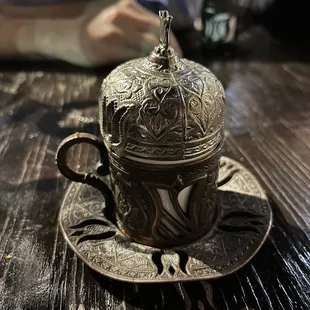 a silver cup and saucer on a wooden table