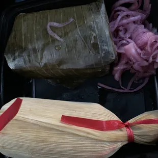 Cochinita Oaxaqueno (wrapped in banana leaf), Tica de Pollo Norte (wrapped in corn husks) and pickled onions.