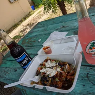 a plastic container of food and a bottle of soda