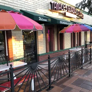 the outside of a restaurant with tables and umbrellas