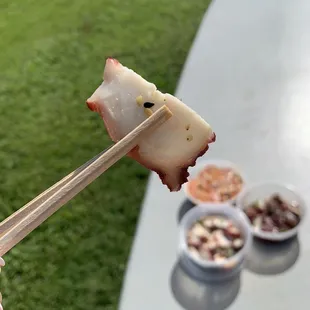 a person holding a chopstick with a piece of meat on it