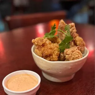 a bowl of fried chicken with a side of dipping sauce