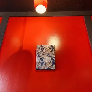 a red wall with a square tile on it