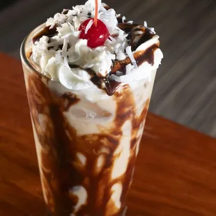 a chocolate milkshake with whipped cream and a cherry on top