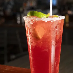 a red cocktail with lime garnish