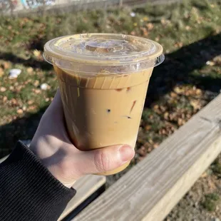 a hand holding a cup of iced coffee