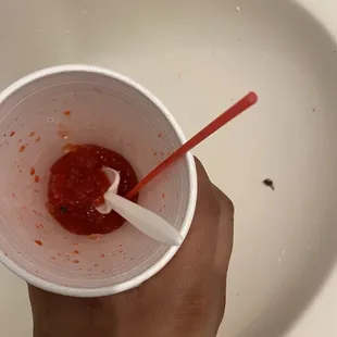 a person holding a cup of ketchup