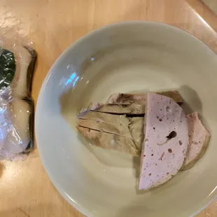a plate of food and a sandwich wrapped in plastic wrap