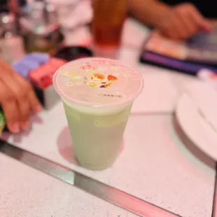 a person sitting at a table with a drink in a plastic cup