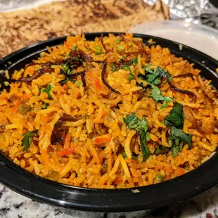 Chicken biryani. Chunks of chicken cooked in basmati rice with nuts and spices. $14. Comes with a small side of raita.