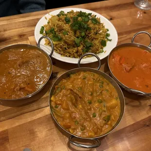 a variety of curry dishes on a wooden table