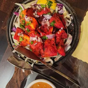 Tikka Kabob on a steaming hot iron plate with onions roasting in-between.