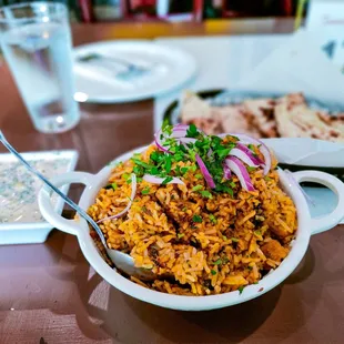 a bowl of rice with onions and herbs