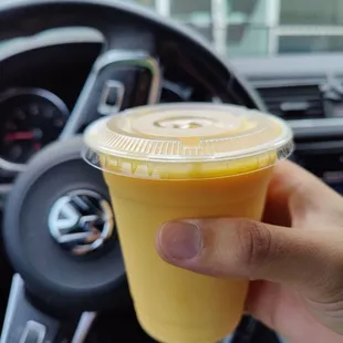 a hand holding a cup of orange juice