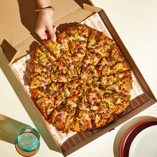 a person grabbing a slice of pizza
