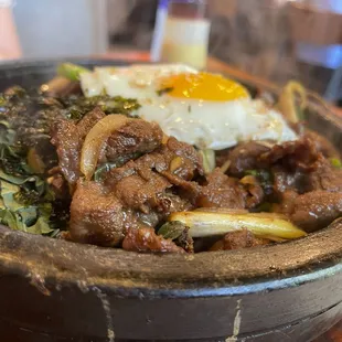 Bulgogi Rice Plate. Marinated and grilled beef &apos;BiBim-Bop&apos;, on a sizzling hot stone plate with onion, cabbage, radish, and green onion.