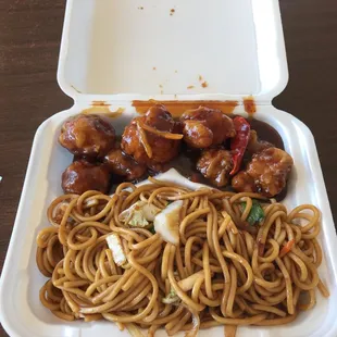 a takeout box with noodles and meatballs