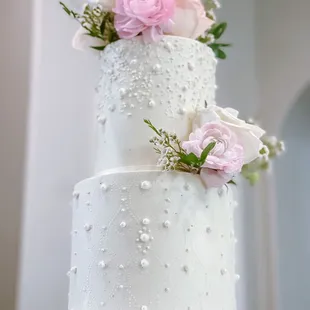 White wedding cake with pearl decorations and fresh florals