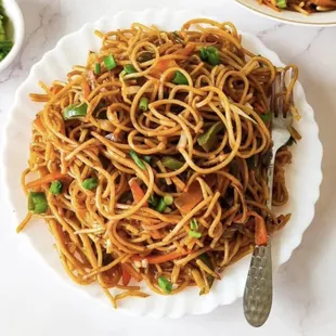 a plate of noodles with peas and carrots