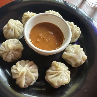 a plate of dumplings and a bowl of dipping sauce