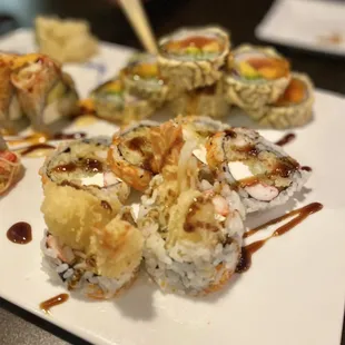 a plate of sushi with sauce and chopsticks