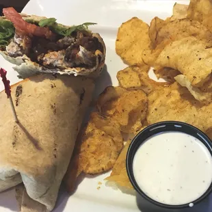 Buffalo chicken wrap with lettuce onion and tomato, with a side of chips and ranch