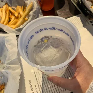 a person holding a plastic cup of ice