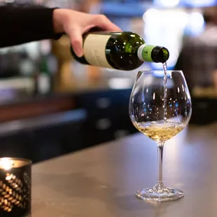 a person pouring a glass of wine