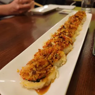 a long rectangular plate of sushi on a wooden table