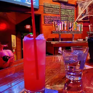 a glass of water and a drink on a bar