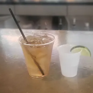 a glass of iced tea with a straw and a lime wedge