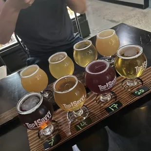 a man taking a picture of a flight of beers