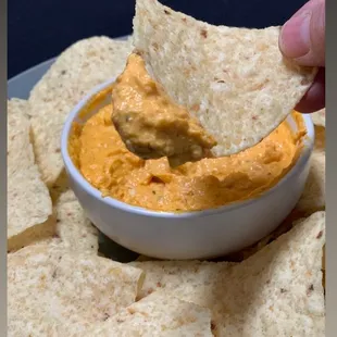 a hand dipping tortilla into a bowl