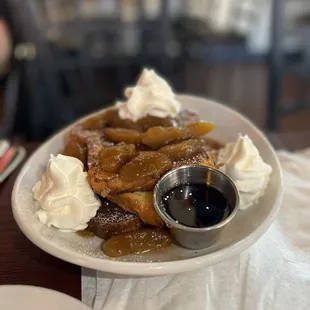 a plate of french toast with whipped cream and syrup