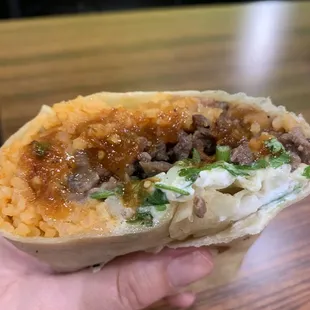 Carne Asada Burrito  with rice, beans, cheese, onion, cilantro and sour cream.  Red salsa on the side