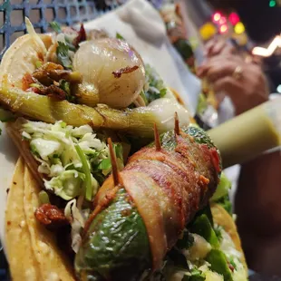 a hotdog with bacon, onions, and lettuce