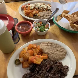 a plate of beef, potatoes, beans, and salsa